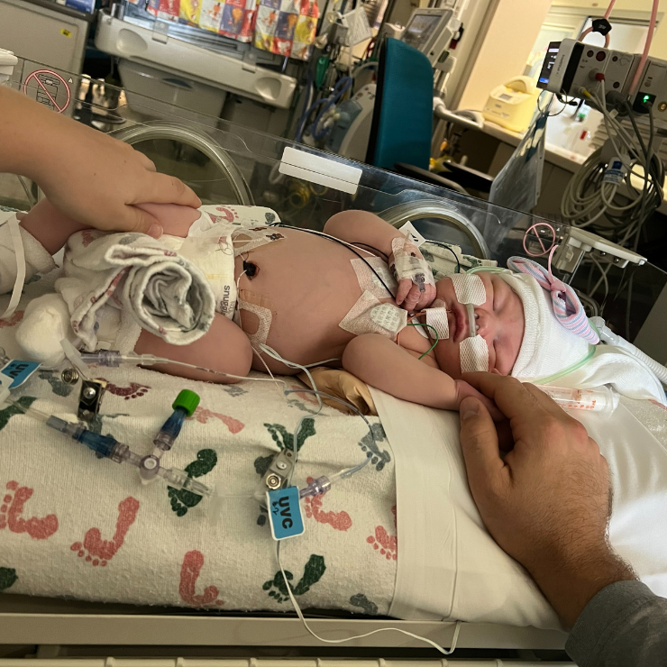 A newborn baby laying in the hospital with tubes and wires.
